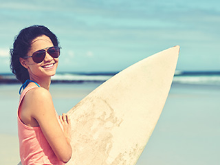 woman in sunglasses holding surfboard